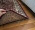 Illustrative scene of hands lifting a wool rug edge for inspection